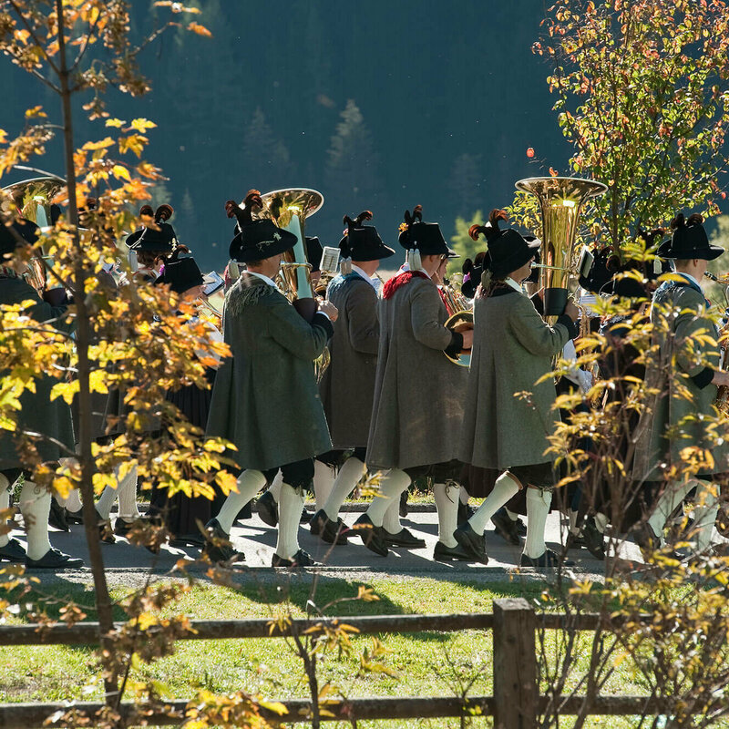 Fest im Herbst Zwischen zwei verfärbten Bäume sieht man Häuser eines Dorfes.