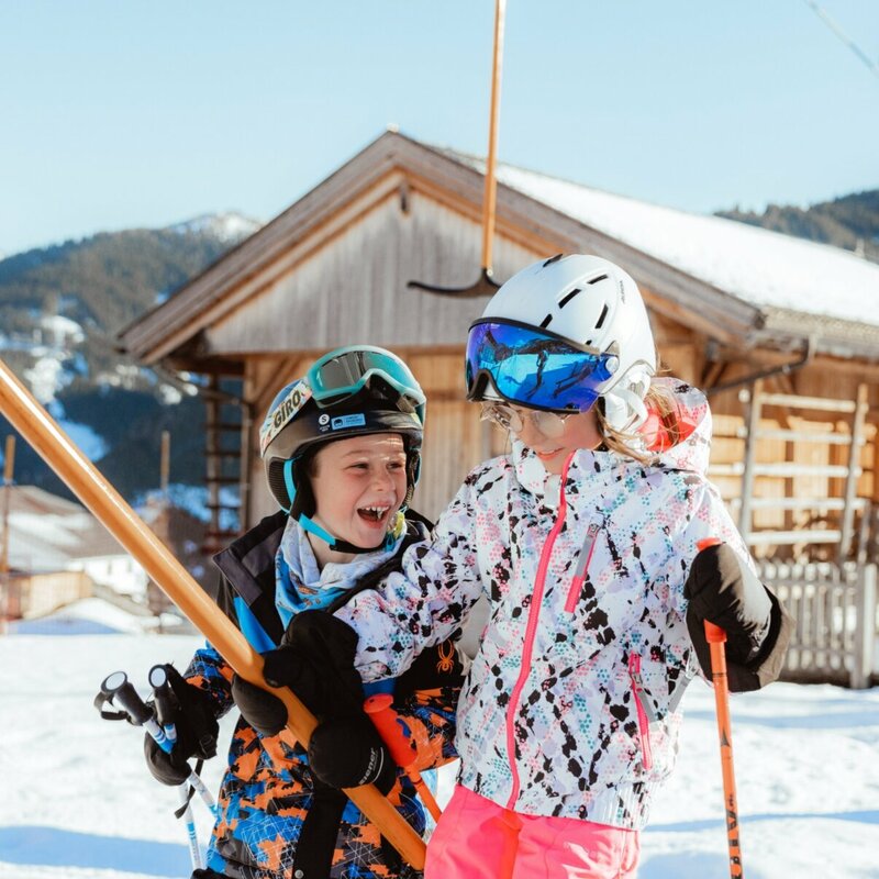 Zwei Kinder lassen sich vom Schlepplift im Familienskigebiet Golzentipp in Obertilliach auf den Berg ziehen.