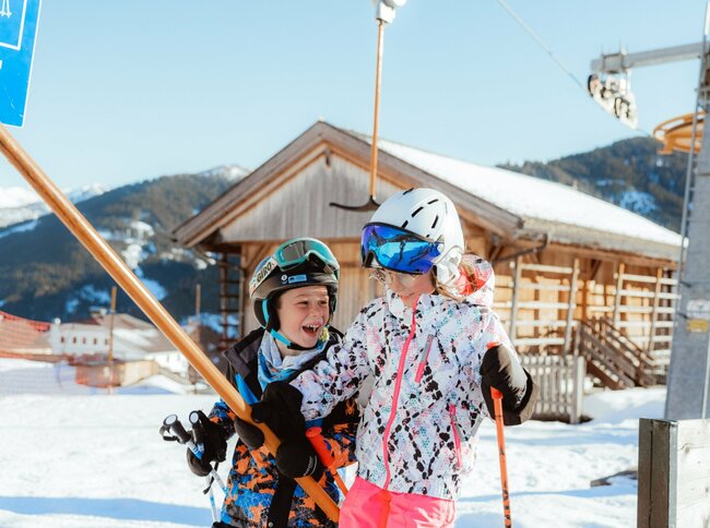 Zwei Kinder lassen sich vom Schlepplift im Familienskigebiet Golzentipp in Obertilliach auf den Berg ziehen.
