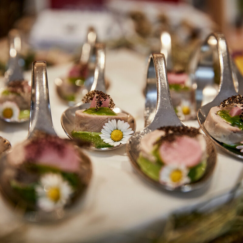 Haubenküche Gannerhof Haubenküche im Gannerhof - Gericht bestehend aus einem runden Fleischstück mit einer grünen Soße verziert mit einem Gänseblümchen auf einem Löffel angerichtet.