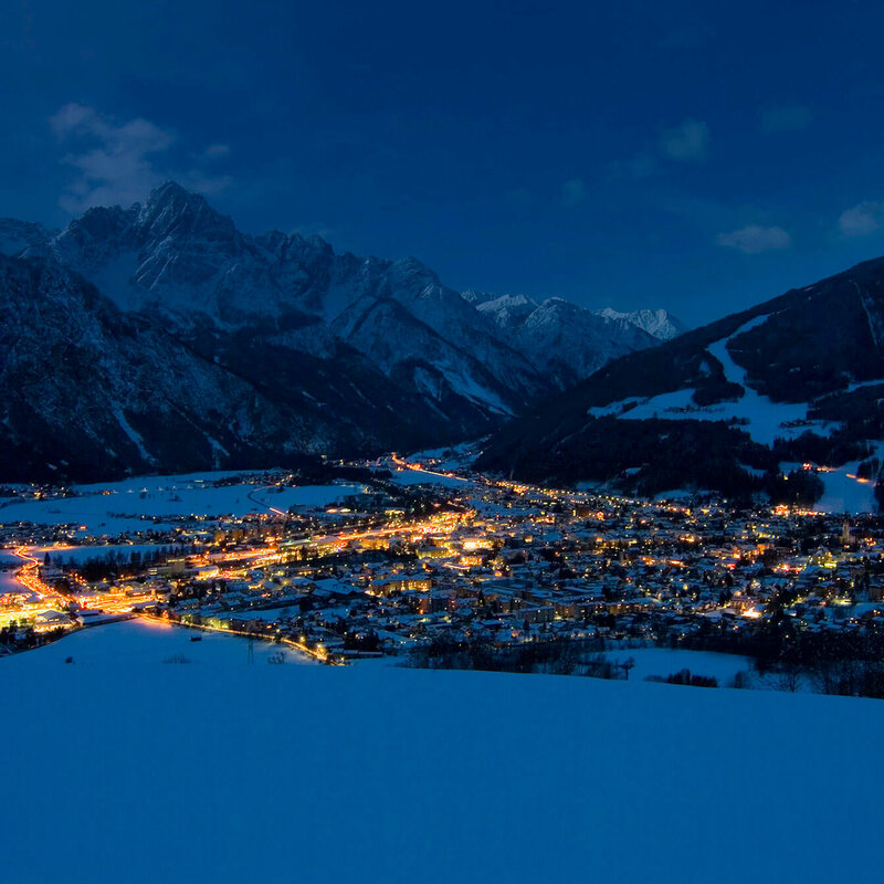 Lienz Blick auf den Lienzer Talboden in einer klaren Winternacht. Die Lichter der Stadt erhellen die Nacht.