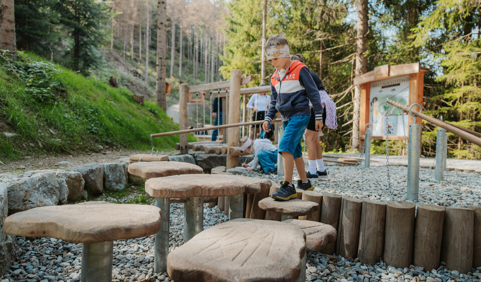 Ein Junge balanciert auf einer Konstruktion auf dem Waldwichtelweg.