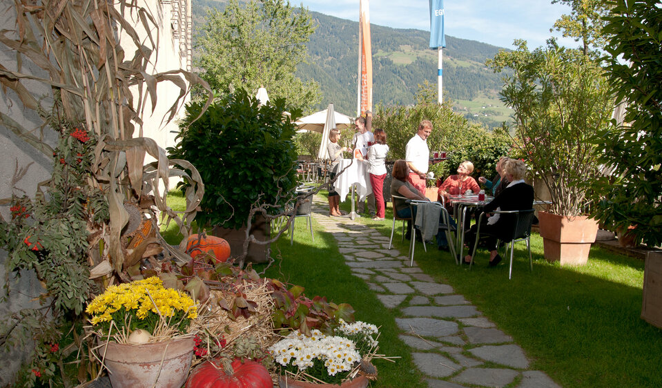 Gäste sitzen auf der Terrasse des Cafés im Schloss Bruck in Lienz, umgeben von sommerlicher Atmosphäre