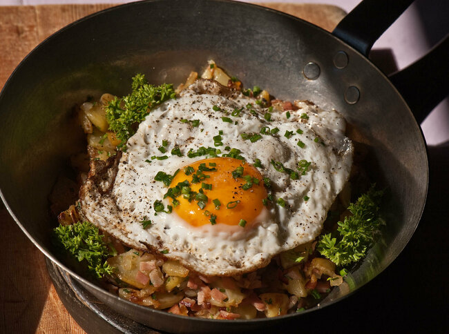 Tiroler Gröstl mit Spiegelei und Schnittlauch in einer kleine Eisenpfanne.