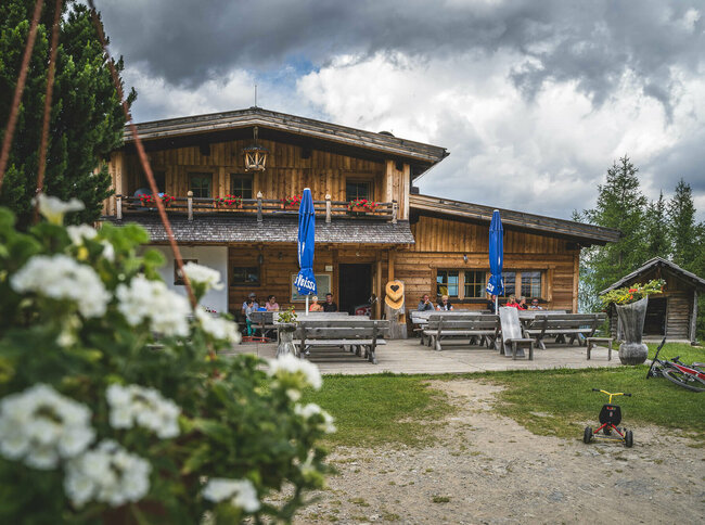 Leckfeldalm Blick auf die urige Leckfeldalm, mit Gaesten auf der Terrasse.