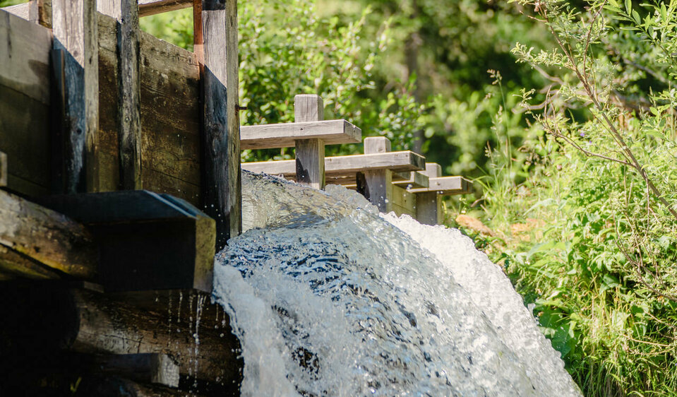 Hinabschießendes Wasser einer Mühle im Freilichtmuseum Alpines Leben in Innervillgraten
