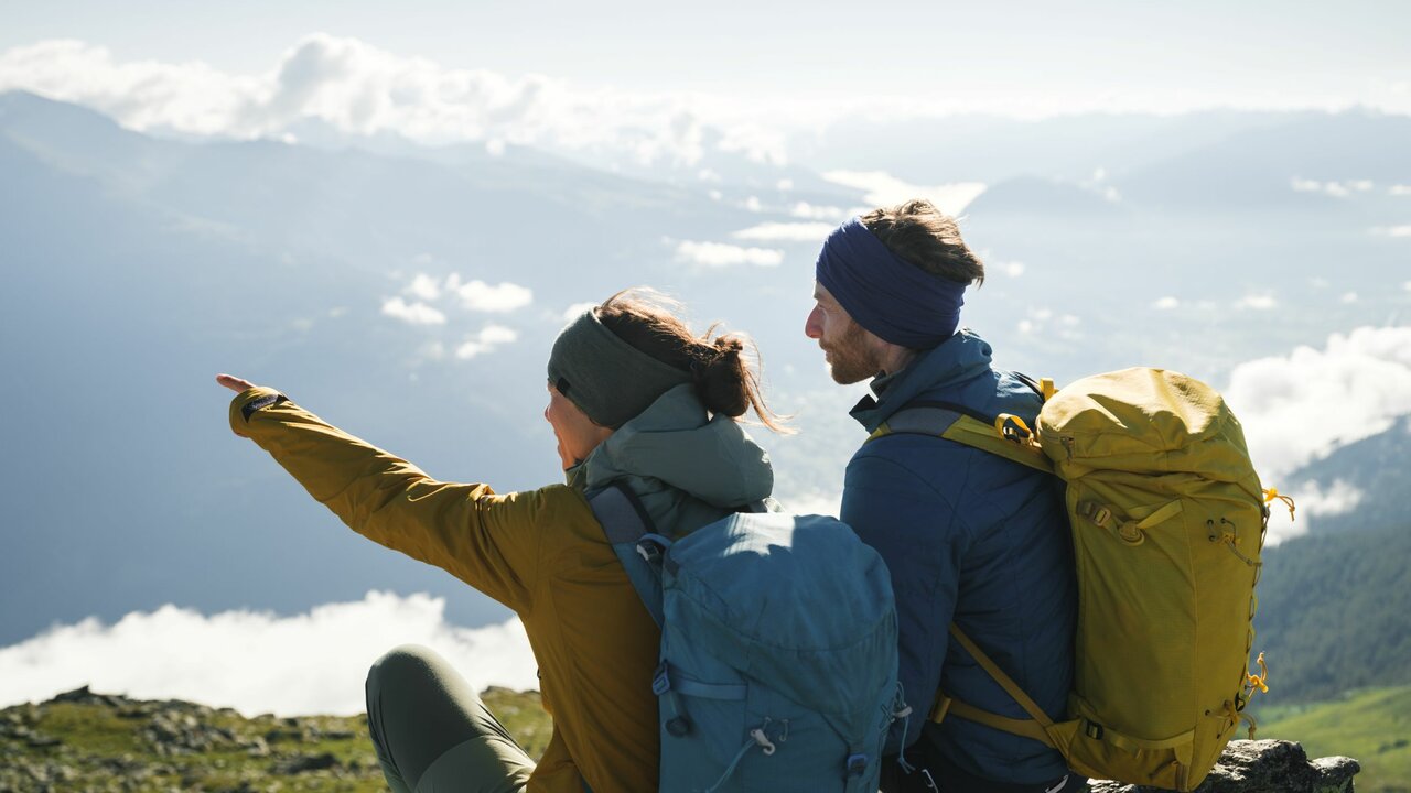 Ein Paar mit Rucksäcken genießt die Aussicht am Bösen Weibele. Die Frau zeigt dem Mann etwas in der Ferne.