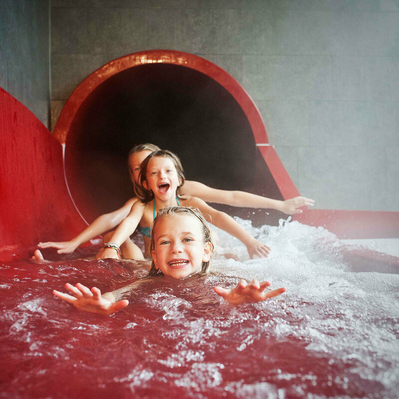 Dolomitenbad Lienz Drei Mädchen am Ausgang einer roten Wasserrutsche im Dolomitenbad in Lienz.
