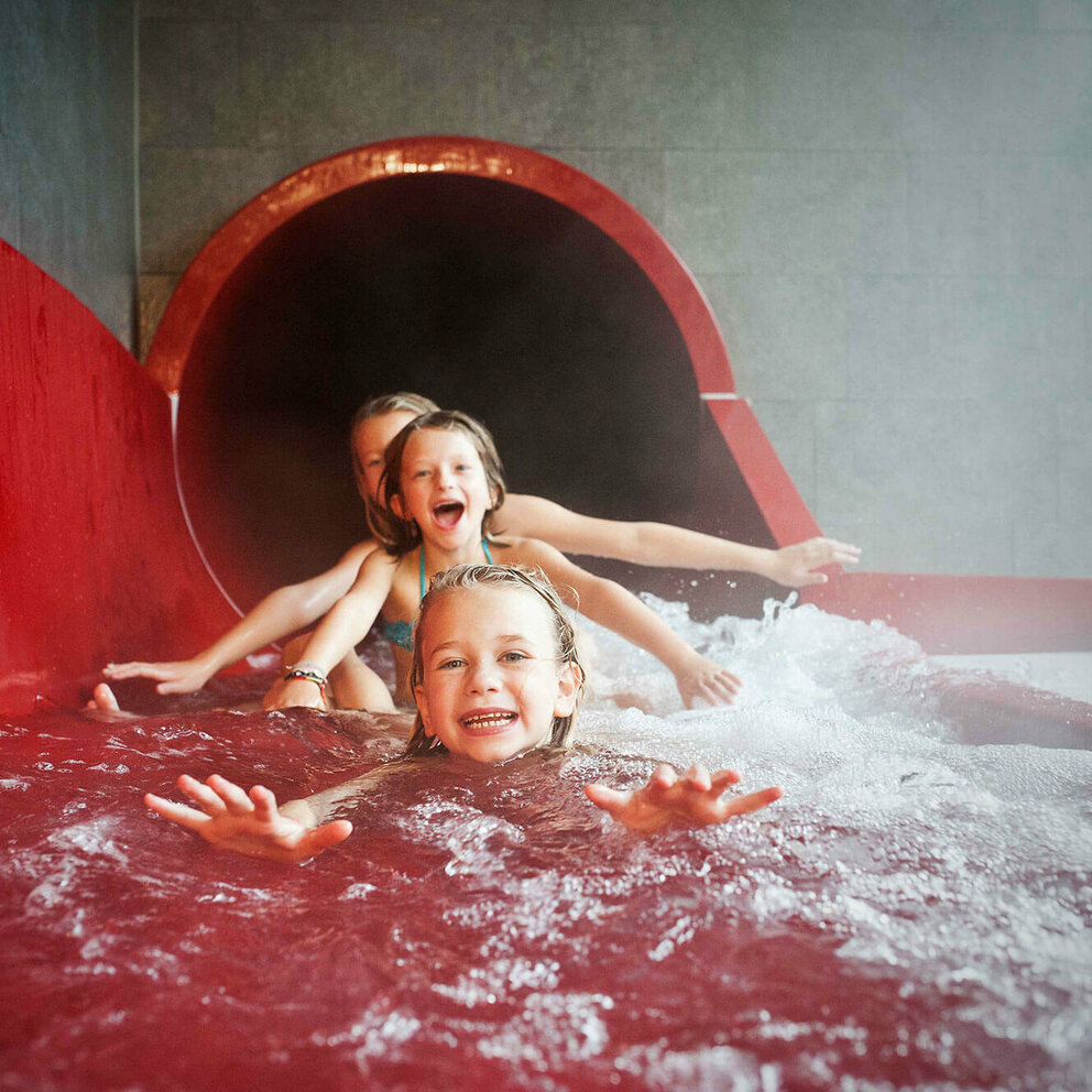 Dolomitenbad Lienz Drei Mädchen am Ausgang einer roten Wasserrutsche im Dolomitenbad in Lienz.