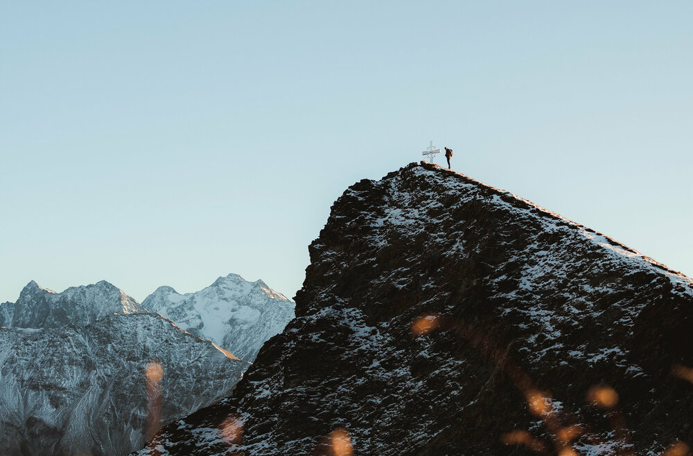 Das Figerhorn in Kals am Großglockner ist ein beeindruckender Gipfel mit Blick auf die Glocknergruppe. Wanderer am Gipfel des Figerhorns im Herbst mit schon einigen Schneefeldern auf den Bergen.