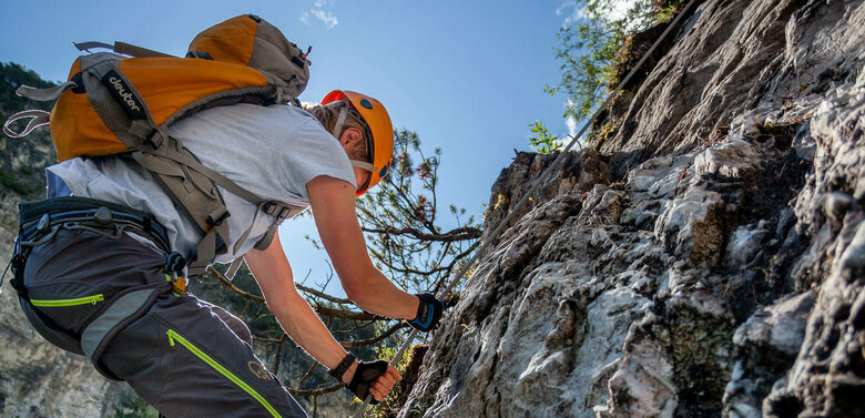 Nahaufnahme von einem Mann mit orangenem Helm und Rucksack auf dem Klettersteig Dopamin in der Galitzenklamm in Osttirol.