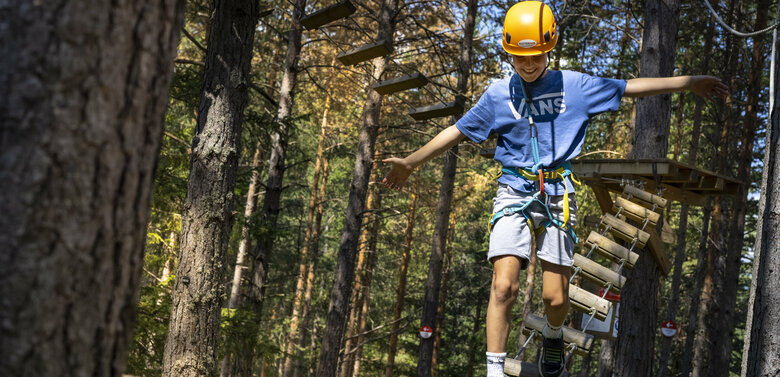 junger Kletterer im Kletterpark Moosalm Ein junger Kletterer zeigt seine Geschicklichkeit im Kletterpark Moosalm in Lienz in Osttirol.