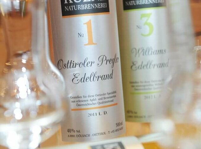 Osttiroler Pregler Vor zwei Flaschen Osttiroler Pregler liegt eine Flasche und davor ist ein leeres Schnapsglas anschaulich positioniert.