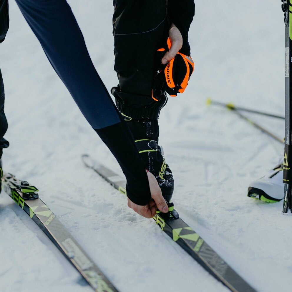 Langläufer Obertilliach Nahaufnahme eines Langläufers beim Justieren seiner Langlaufskier in Obertilliach.