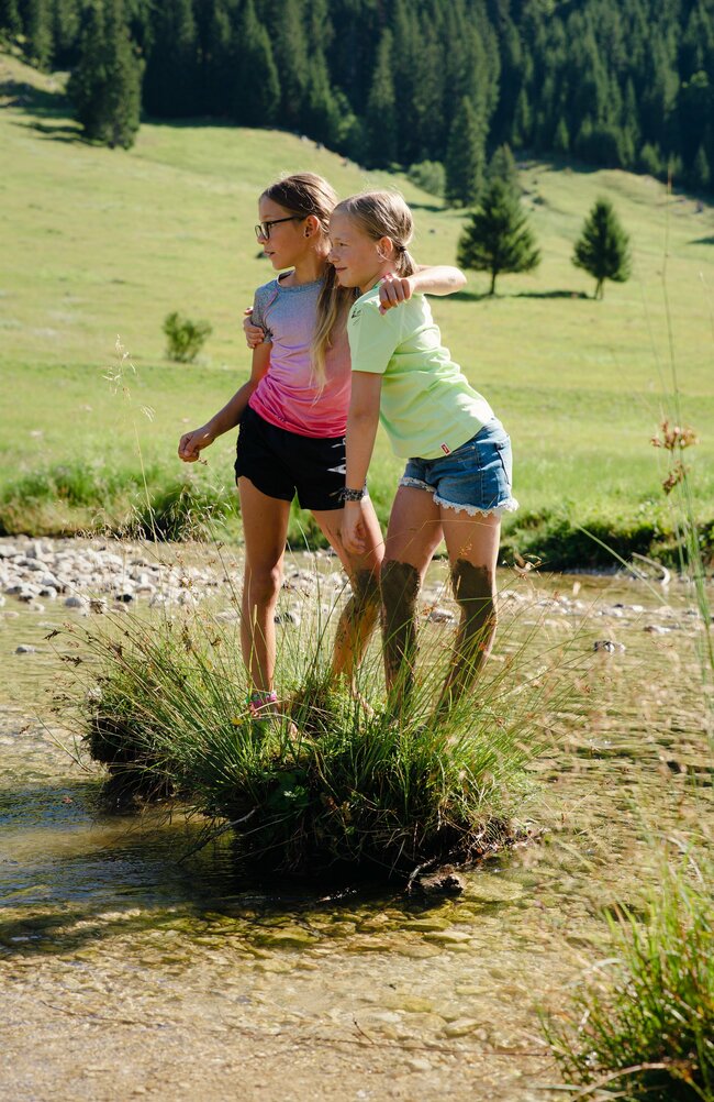 Zwei Mädchen stehen im kleinen See und posieren für ein Foto.