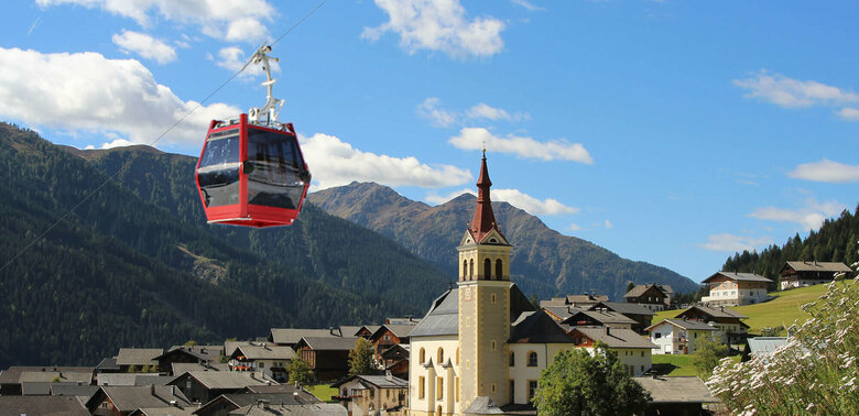 Obertilliach Bergbahn Sommergondel Sommergondel der Obertilliach Bergbahn fährt am Tal und der Kirche Obertilliachs vorbei
