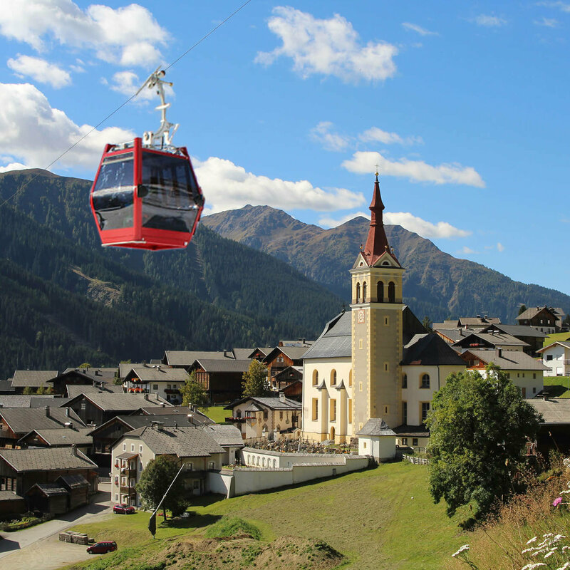 Obertilliach Bergbahn Sommergondel Sommergondel der Obertilliach Bergbahn fährt am Tal und der Kirche Obertilliachs vorbei