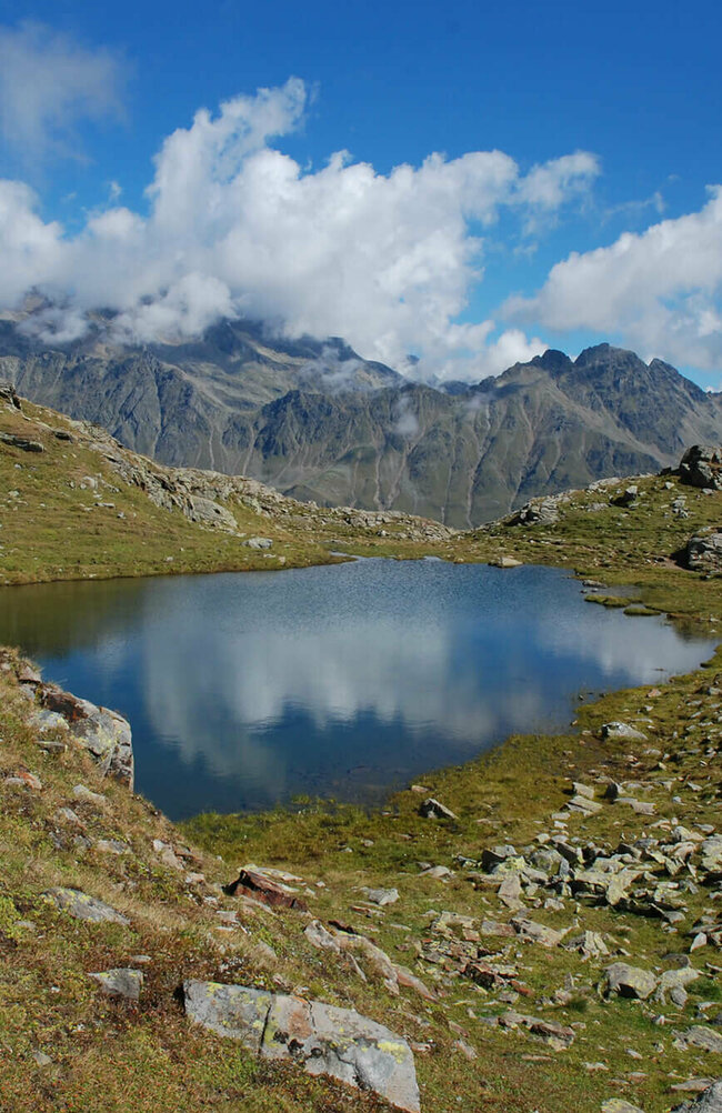 Neualpenseen Zettersfeld Einer der Neualpenseen am Lienzer Zettersfeld, im Vordergrund der klare Bergsee, im Hintergrund ein mächtiges Bergmassiv unter blauem Himmel.