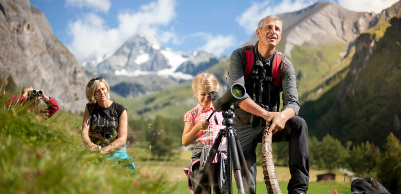 Wildtierbeobachtung Eine Familie bei der Wildtierbeobachtung. Ein Mädchen blickt durch ein Fernglas im Nationalpark Hohe Tauern.
