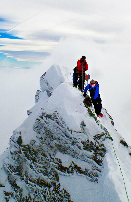 Zwei Bergsteiger:innen erklimmen den Gipfle des Kleinglockner
