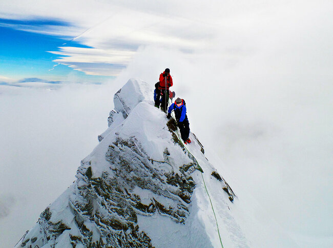 Zwei Bergsteiger:innen erklimmen den Gipfle des Kleinglockner