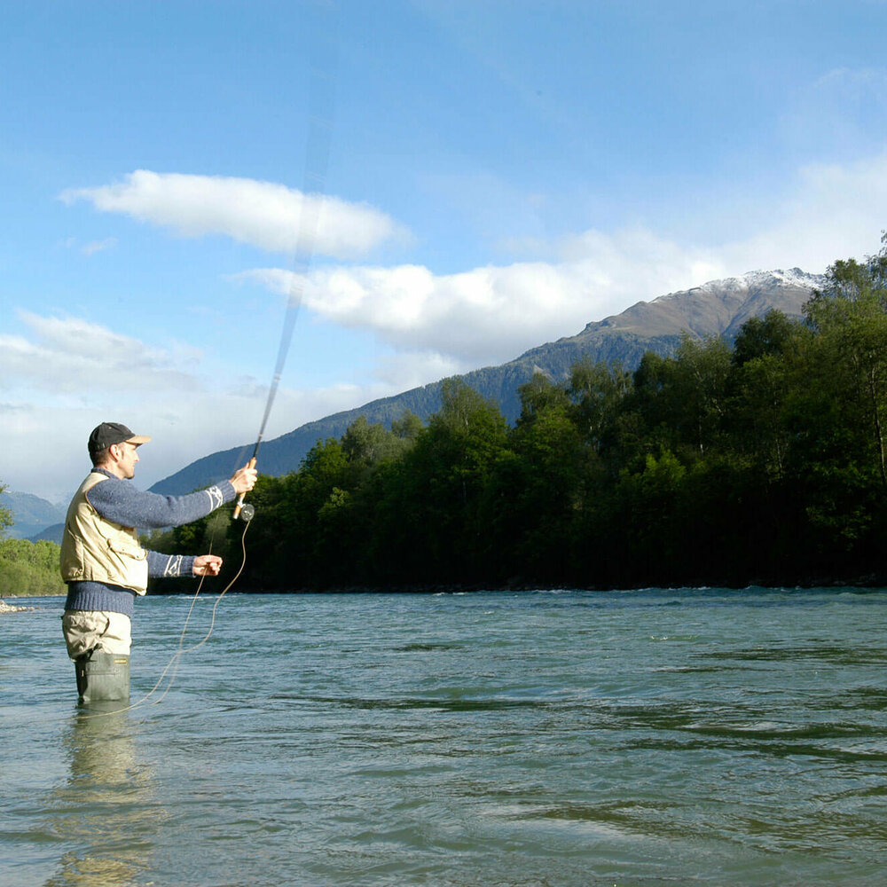 Fliegen fischen Ein Mann steht in einem Fluss und wirft seine Angel aus zum Fliegen fischen.