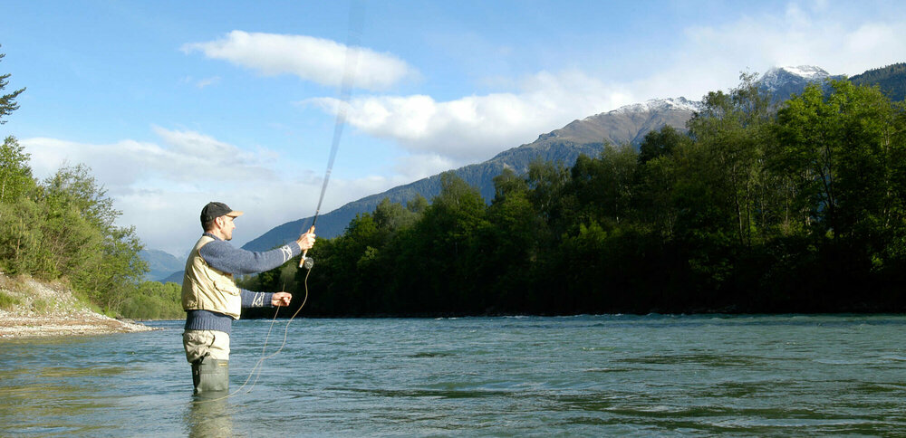 Fliegen fischen Ein Mann steht in einem Fluss und wirft seine Angel aus zum Fliegen fischen.