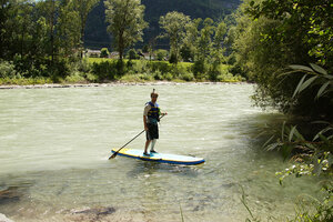 Stand Up Paddle Eine Person mit Schwimmweste und Helm steht auf einem Stand Up Paddle Board auf der Isel.