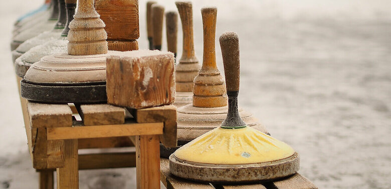 Eine hölzerne Bank voll Equipment zum Eisstockschießen.