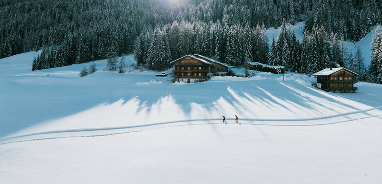 Langlaufloipe in Innervillgraten bei strahlendem Sonnenschein und eine frisch verschneitem Wald im Hintergrund