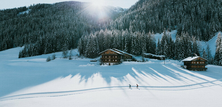 Langlaufloipe in Innervillgraten bei strahlendem Sonnenschein und eine frisch verschneitem Wald im Hintergrund