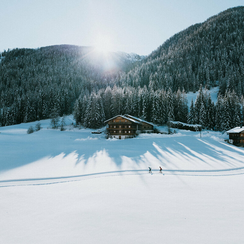 Langlaufloipe in Innervillgraten bei strahlendem Sonnenschein und eine frisch verschneitem Wald im Hintergrund