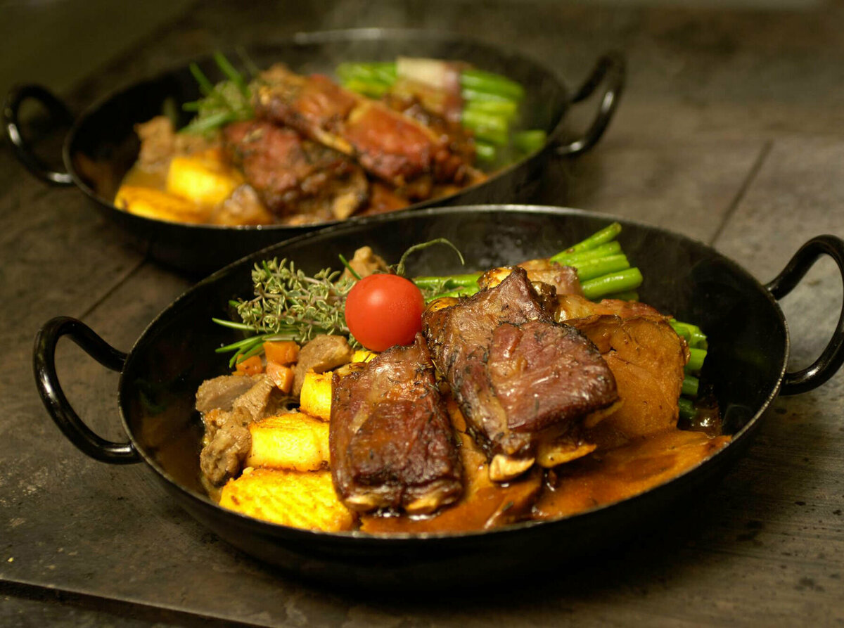 Osttiroler Berglamm Osttiroler Berglamm mit Speckbohnen und Polenta in einem Eisenpfännchen.