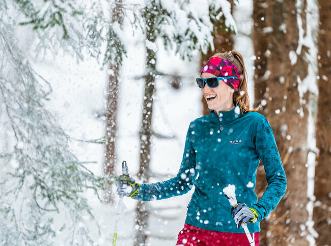 Frau beim Langlaufen in Obertilliach im verschneitem Wald