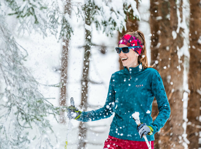 Frau beim Langlaufen in Obertilliach im verschneitem Wald