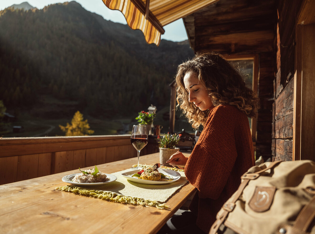 Schlipfkrapfen Unterstaller Alm Eine Frau genießt eine Portion Schlipfkrapfen auf der Terasse der Unterstaller Alm