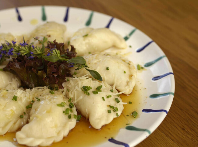 Ostiroler Schlipfkrapfen Osttiroler Schlipfkrapfen mit Schnittlauch und geschmolzener Butter auf einem weiß-blauen Teller, mit etwas Salat verziert.