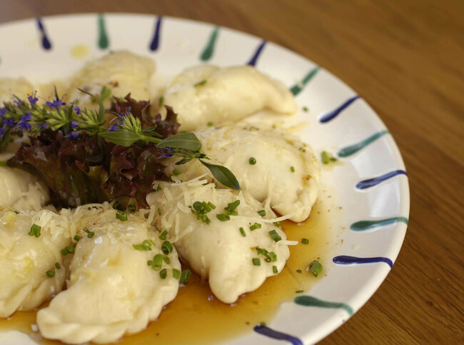 Ostiroler Schlipfkrapfen Osttiroler Schlipfkrapfen mit Schnittlauch und geschmolzener Butter auf einem weiß-blauen Teller, mit etwas Salat verziert.