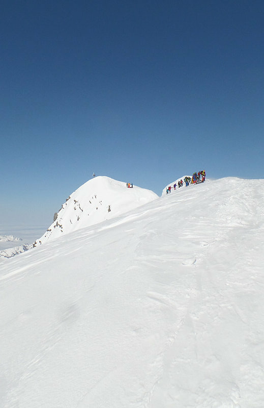 Die letzten Meter vor dem Gipfel des Großvenedigers. Auf dem schneebedeckten Bergrücken stehen einige Bergsteiger.