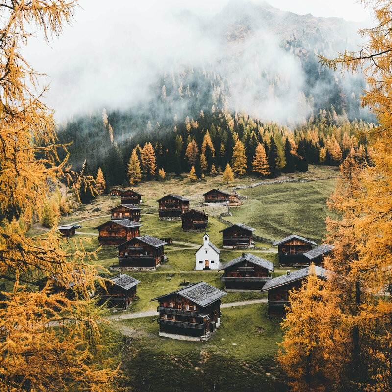 Almhüttendorf "Oberstalleralmen in Innvervillgraten" in herbstlicher Umgebung mit kleiner Kapelle im Zentrum; im Vordergrund goldgelbe Lärchen in Herbstfärbung Almhüttendorf "Oberstalleralmen in Innvervillgraten" in herbstlicher Umgebung mit kleiner Kapelle im Zentrum; im Vordergrund goldgelbe Lärchen in Herbstfärbung
