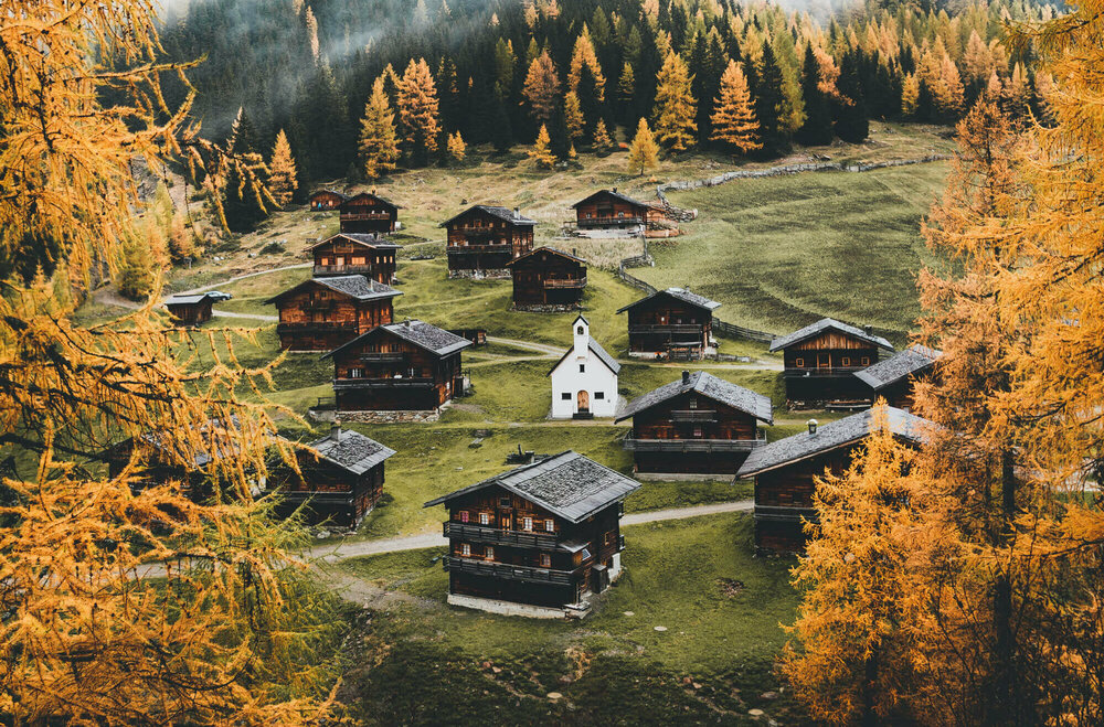 Almhüttendorf "Oberstalleralmen in Innvervillgraten" in herbstlicher Umgebung mit kleiner Kapelle im Zentrum; im Vordergrund goldgelbe Lärchen in Herbstfärbung Almhüttendorf "Oberstalleralmen in Innvervillgraten" in herbstlicher Umgebung mit kleiner Kapelle im Zentrum; im Vordergrund goldgelbe Lärchen in Herbstfärbung