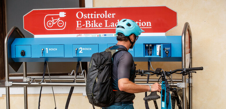 Ein E-Biker lädt sein Bike an der Ladestation Compedalrunde im Kristeinertal im Villgratental in Osttirol.