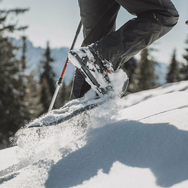 Die Beine eines Mannes beim Schneeschuhwandern durch den Tiefschnee.