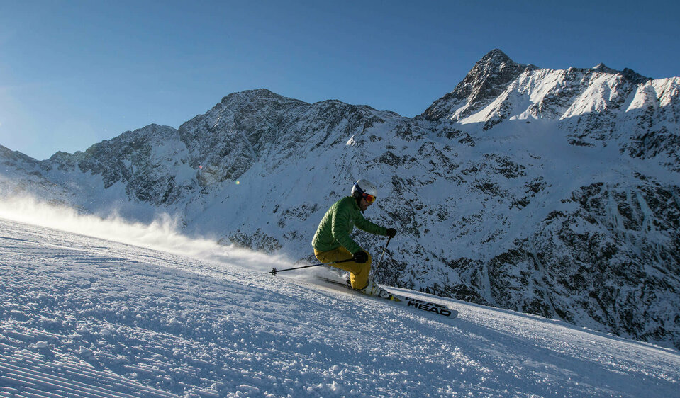Skizentrum St. Jakob Ein Skifahrer mit grüner Jacke und gelber Hose fährt in sportlichem Fahrstil auf der Abfahrt in Skizentrum St. Jakob im Defereggen.