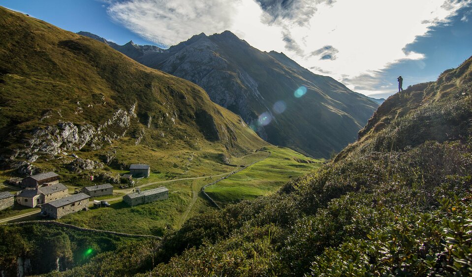 Ein Mensch steht rechts auf einem Hügel und fotografiert von oben die Jagdhausalmen im Defereggental. 