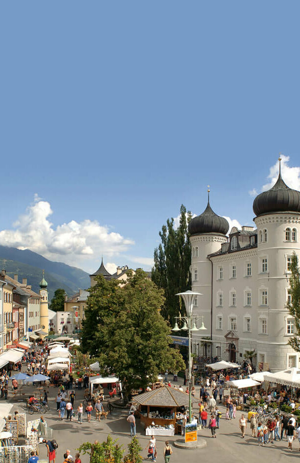 Blick von oben auf den Hauptplatz Lienz mit einigen Marktständen und Besuchern.