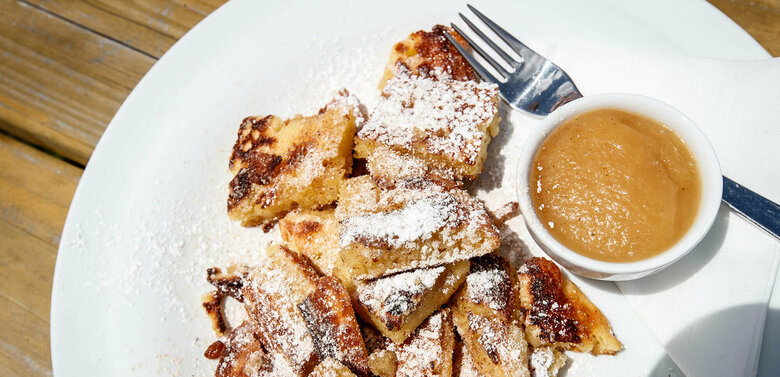 Kaiserschmarren Kaiserschmarren mit Apfelmus in einem separaten Schüsselchen auf einem weißen Teller.