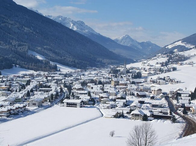 Sillian Ortsansicht von Sillian mit verschneiter Winterlandschaft und Blick auf die Sextener Dolomiten im Hintergrund.