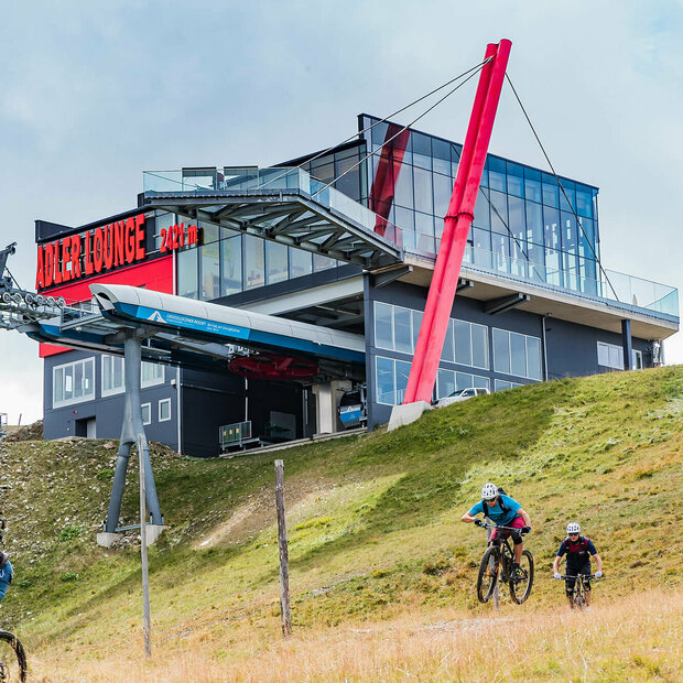 GG Resort Kals Matrei Adler Lounge Zwei talwärts fahrende Mountainbiker unterhalb der Bergstation der Gondelbahn im Großglockner Resort Kals-Matrei