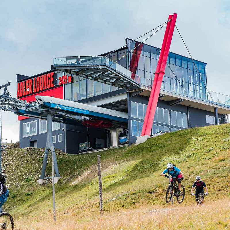 Zwei talwärts fahrende Mountainbiker unterhalb der Bergstation der Gondelbahn im Großglockner Resort Kals-Matrei